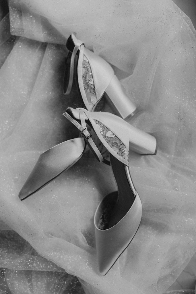 Nahaufnahme von Luisas Brautschuhen und Schmuck auf einem zarten Spitzenstoff. Hochzeitsfotograf Duisburg
