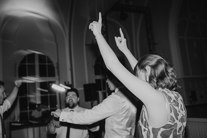 Lebendige Partyfotos von den Gästen auf der Tanzfläche. Der gast hebt die arme in die Luf Stadtgarten Steele Hochzeitsfotograf Esen